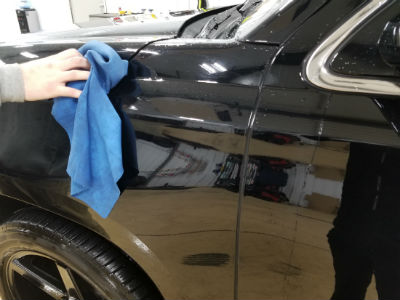 employee drying car exterior with towel